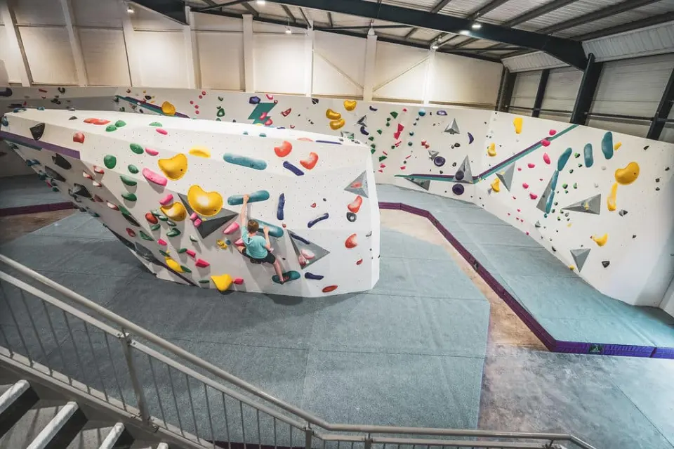 Bouldering hall with a freestanding boulder and long matted walls