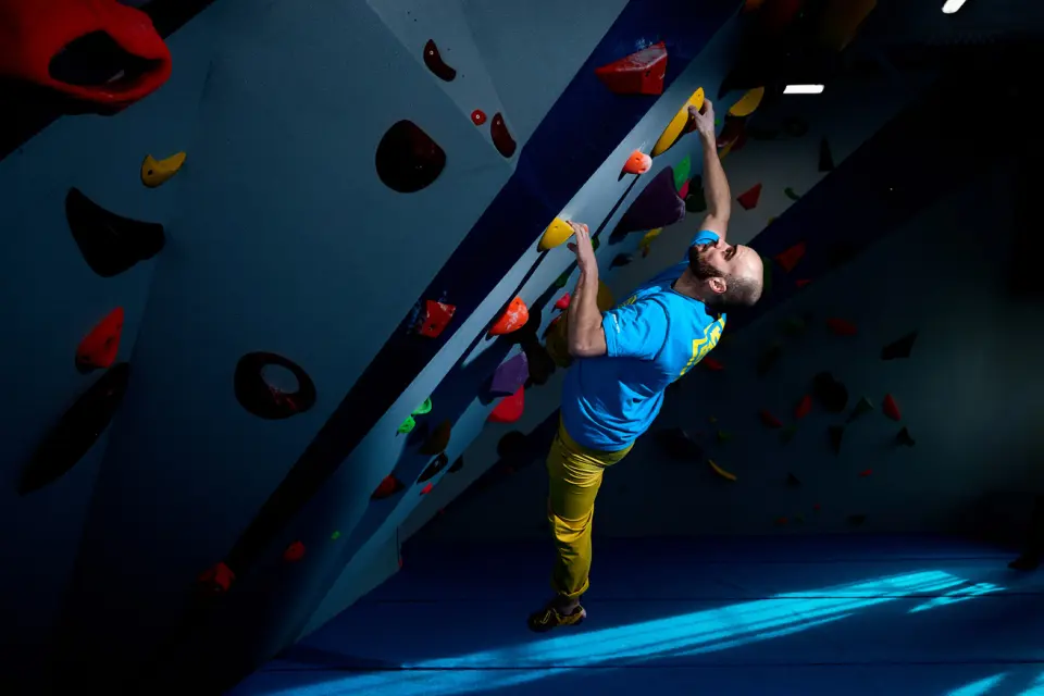 Climber on an overhanging bouldering wall lit by spotlights