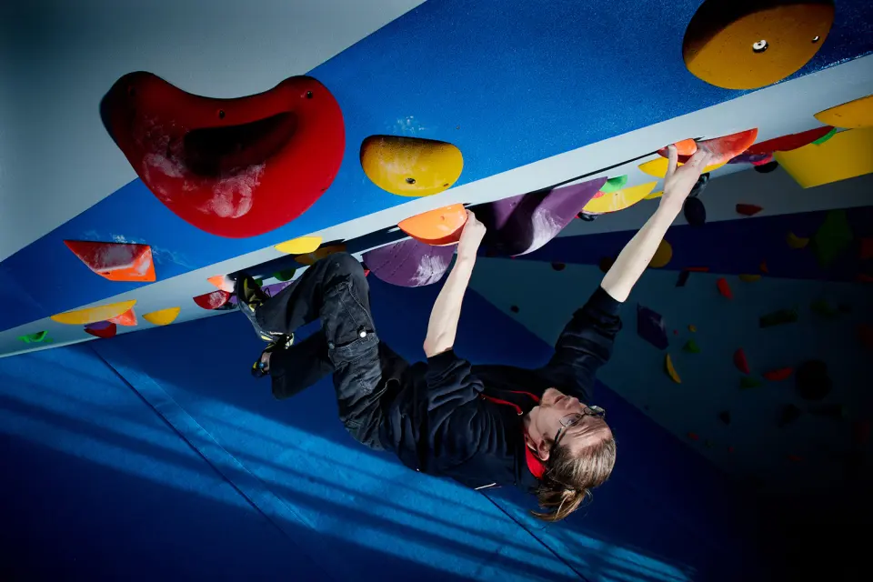 Climber on the bouldering roof with big red and yellow holds