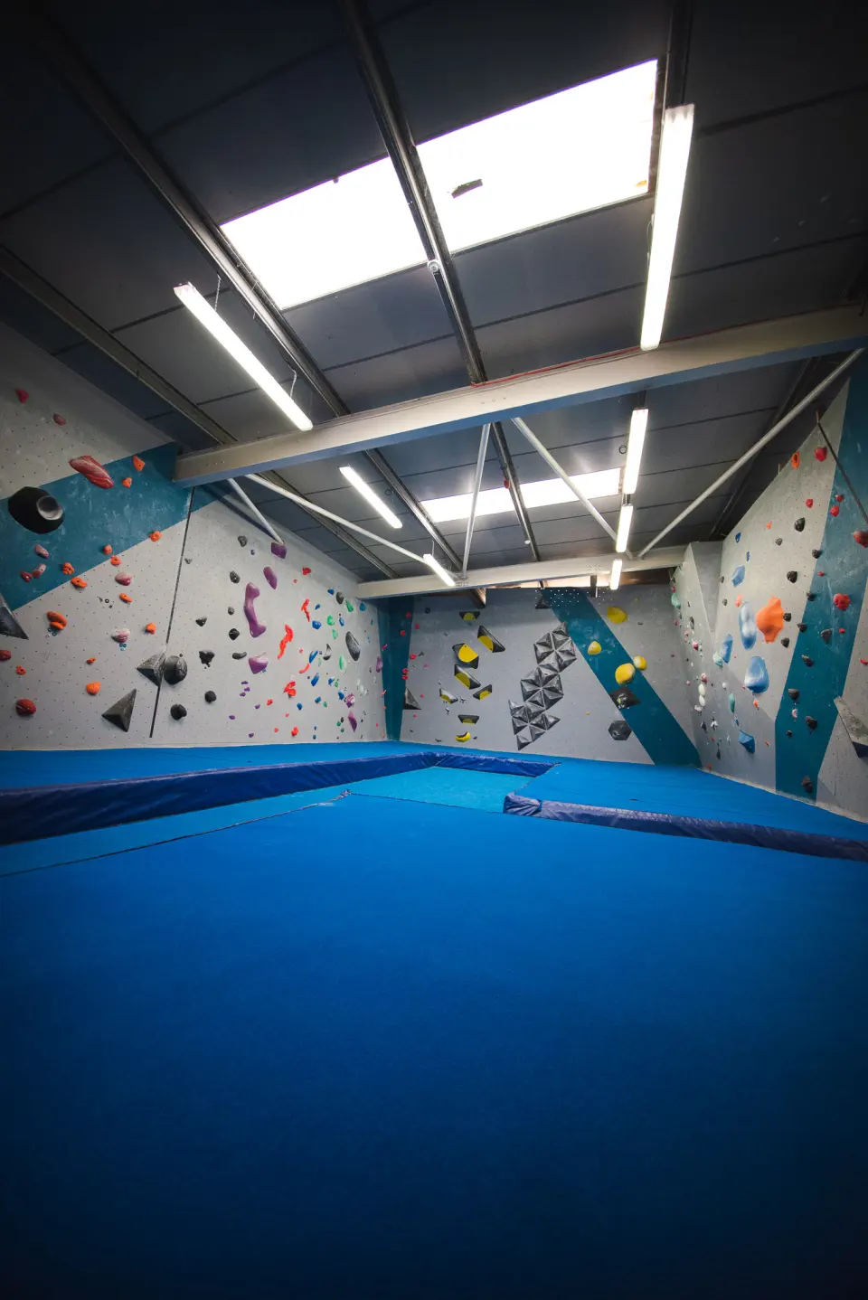 Bouldering room with blue matting and strip lighting