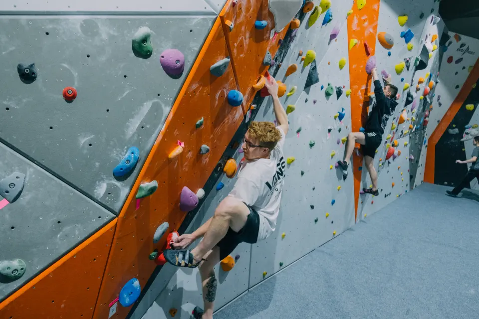 Climber on an orange arete beside grey slab panels