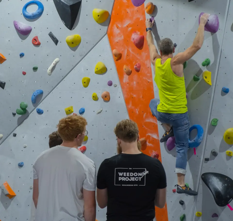 Climber on a vertical wall watched by people below