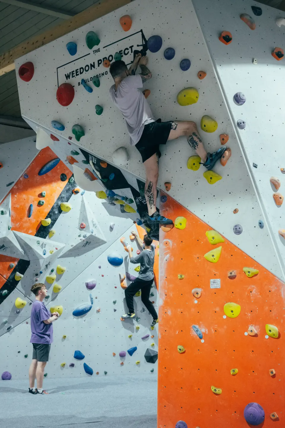 Climbers on a tall white feature with orange panels