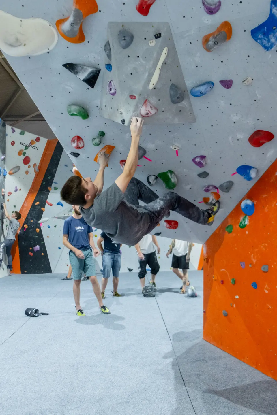 Climber pulling through an overhang on the grey wall