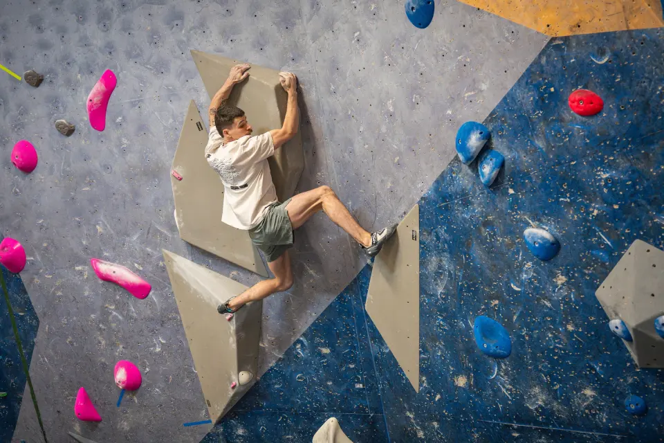 Climber on volumes on a blue and grey wall