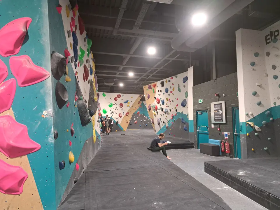 Long bouldering hall with teal and white walls