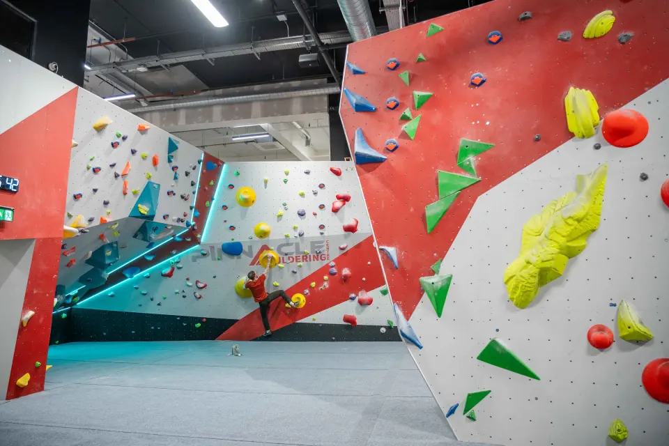 Angled bouldering walls in red, white and teal with LED edging