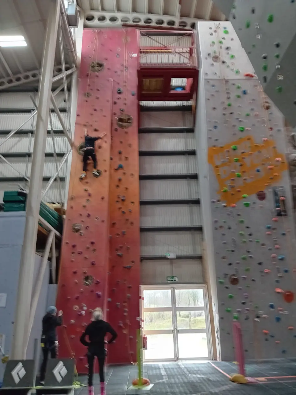 Tall orange and red lead wall beside the grey walls