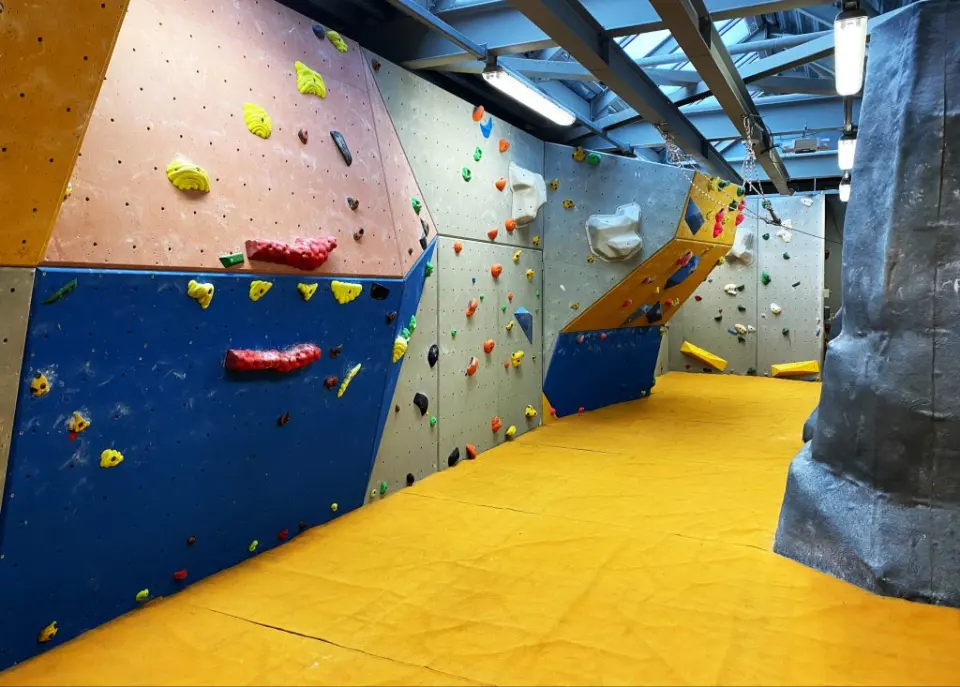 Bouldering loft with yellow matting and blue and orange walls