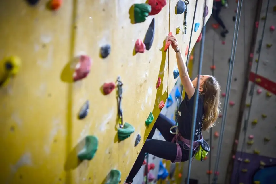 Climber on a top rope on a yellow wall