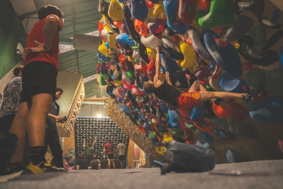 Climber on a steep overhang packed with colourful holds