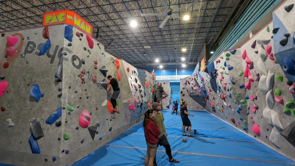 Long bouldering hall with walls on both sides and blue matting