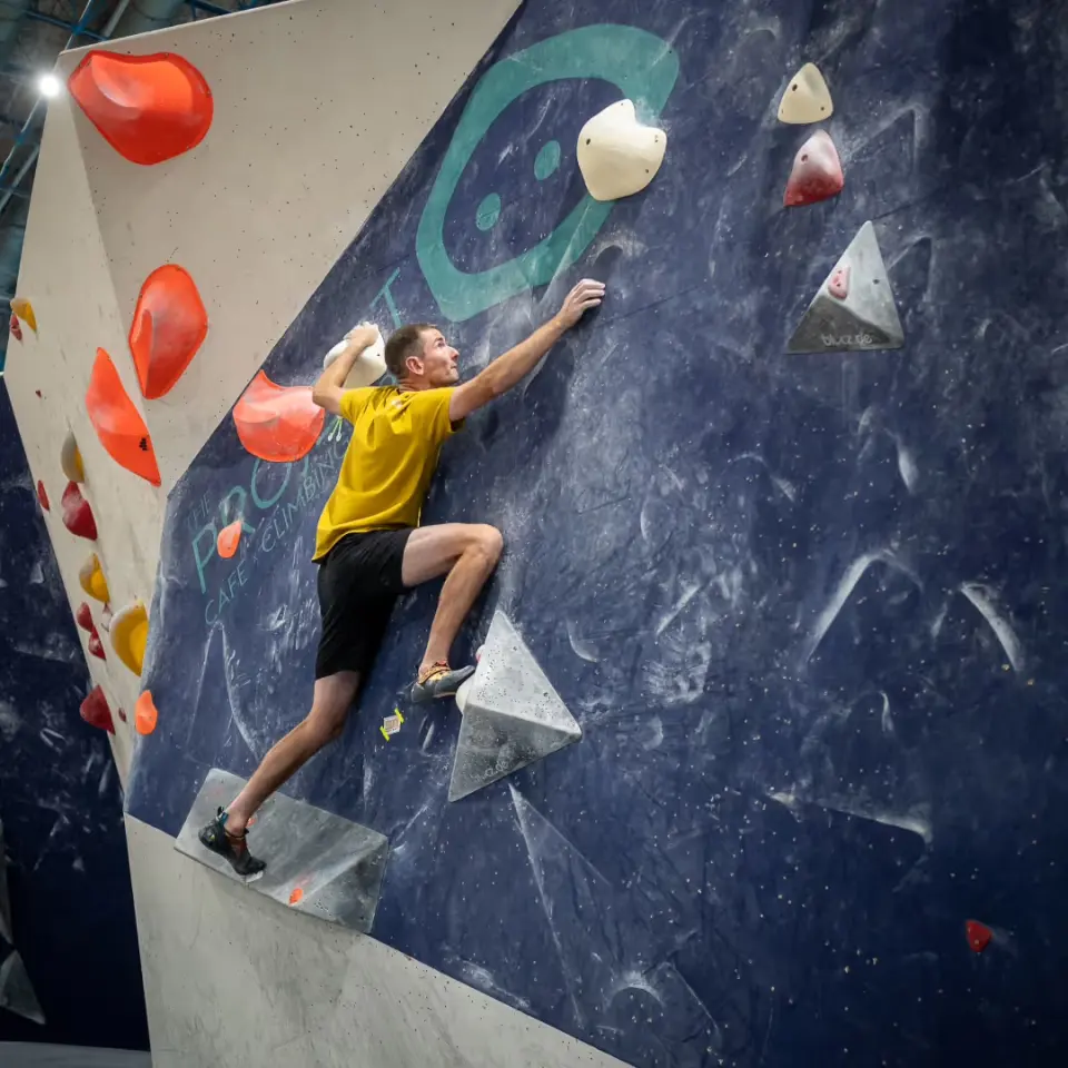 Climber on the navy blue wall with large volumes