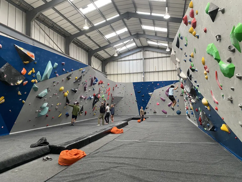 Bouldering room with blue and grey walls above black matting