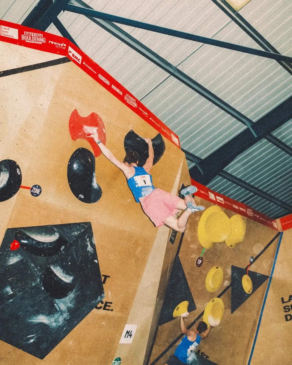 Climber reaching across the competition wall under event banners