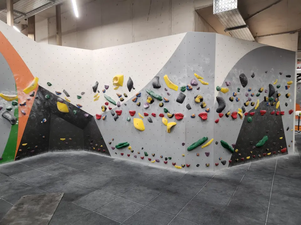Long grey bouldering wall with orange and black panels