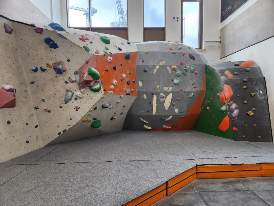 Curved bouldering wall with green and orange panels