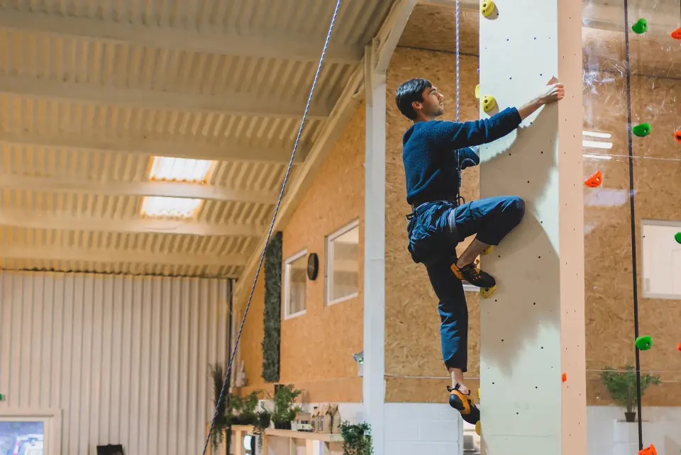 Climber on a top rope up the tall wall
