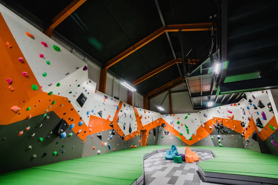 Orange and white bouldering walls around green matting