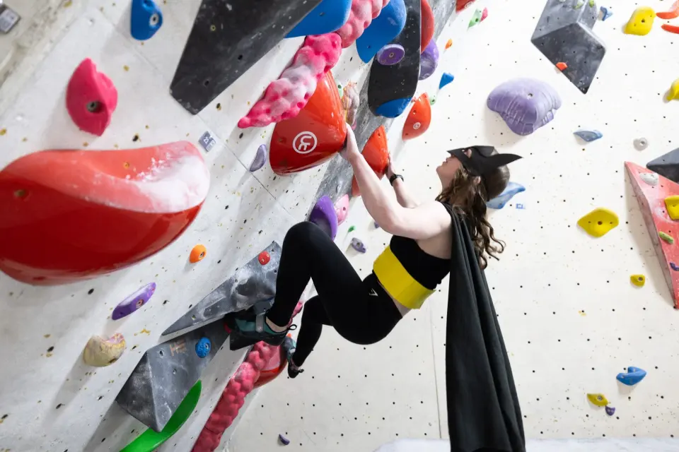 Climber in a cape on a steep boulder problem