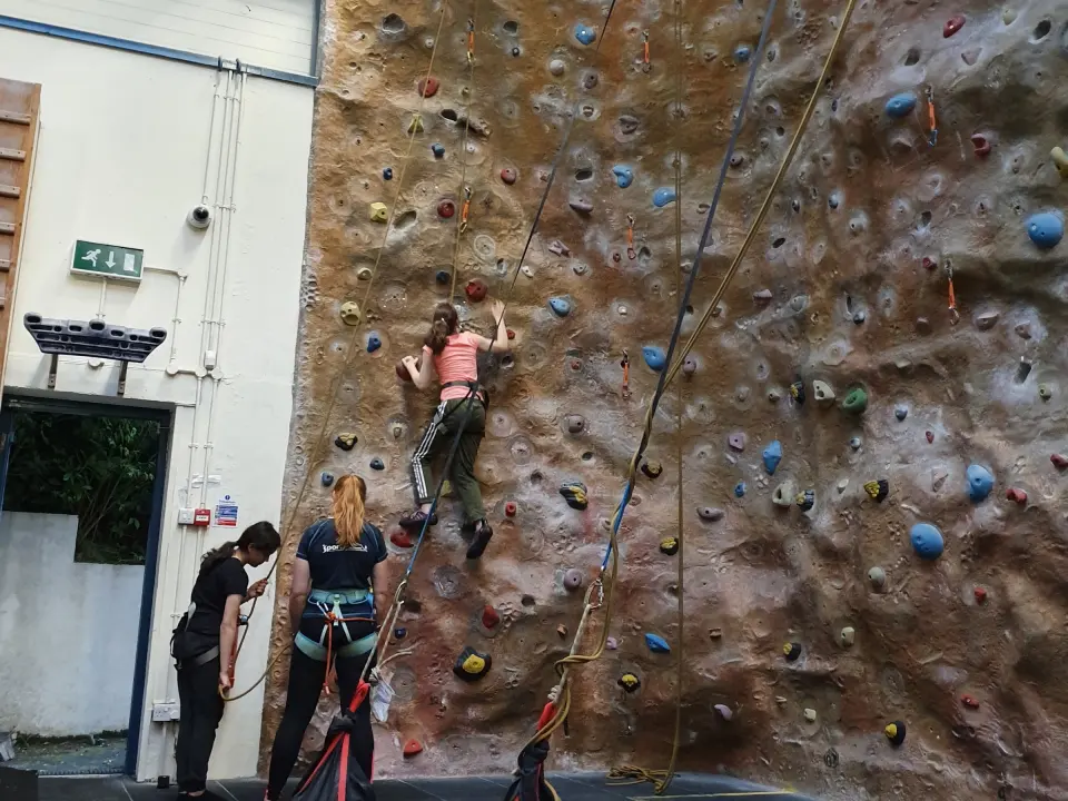 Climber on the textured lead wall with belayers below