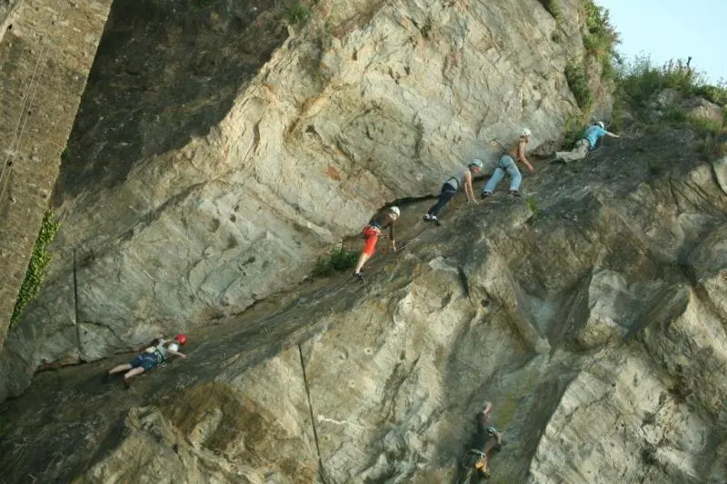 Climbers in helmets crossing the via ferrata on the quarry face