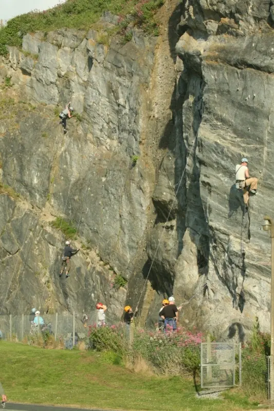 Several climbers on roped routes up the grey quarry face