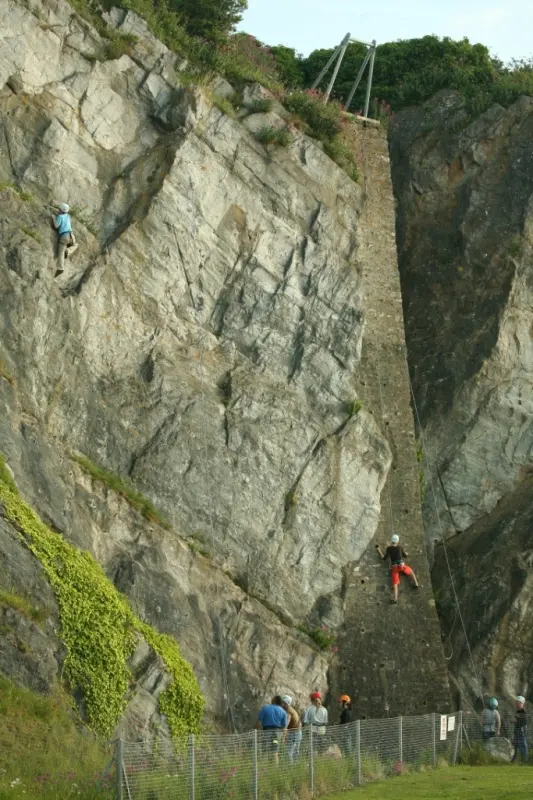 Climbers on the rock face and the abseil tower beside it