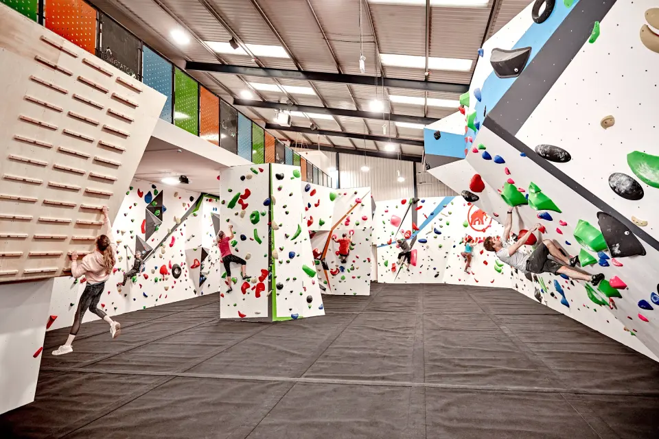 Bouldering hall with climbers, angled walls and the mezzanine above