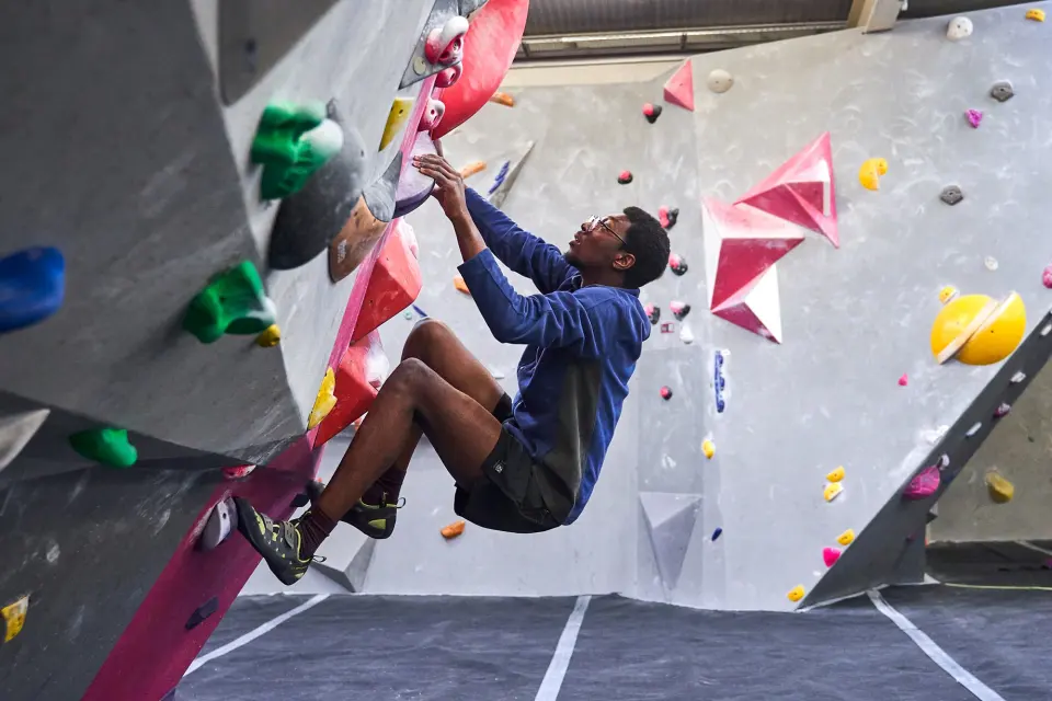 Climber pulling through a steep section with pink holds