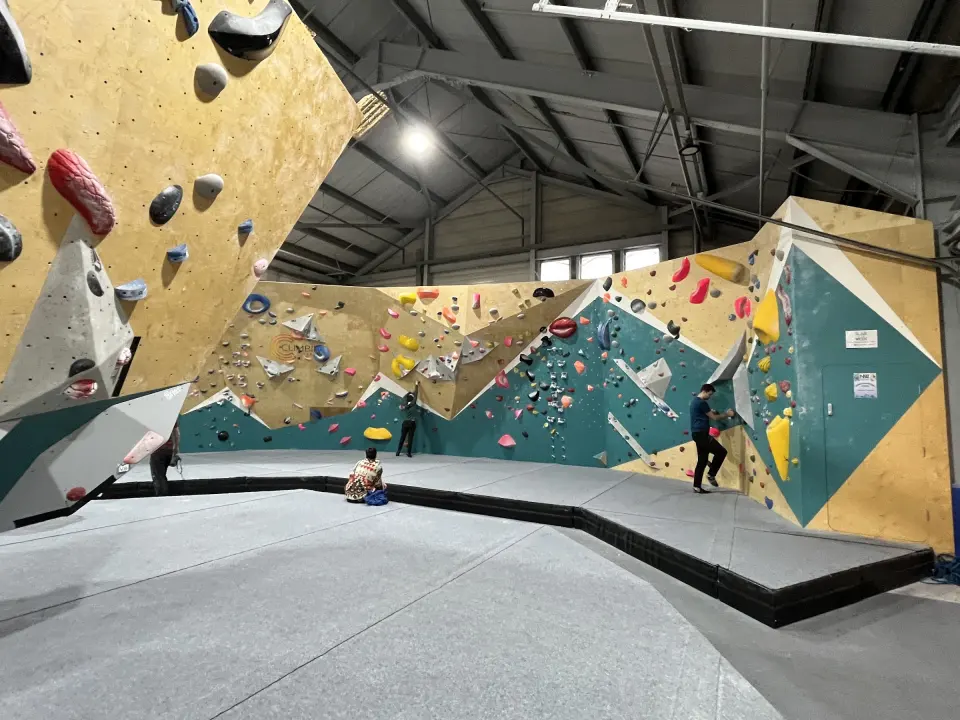 Bouldering hall with teal and plywood walls above grey matting