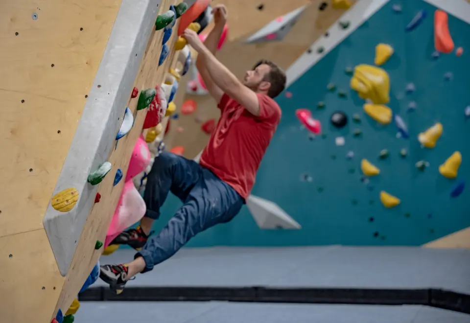 Climber on an arete beside a teal wall