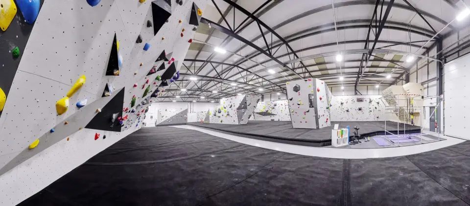 Wide view of the bouldering hall with its grey walls and padded floor