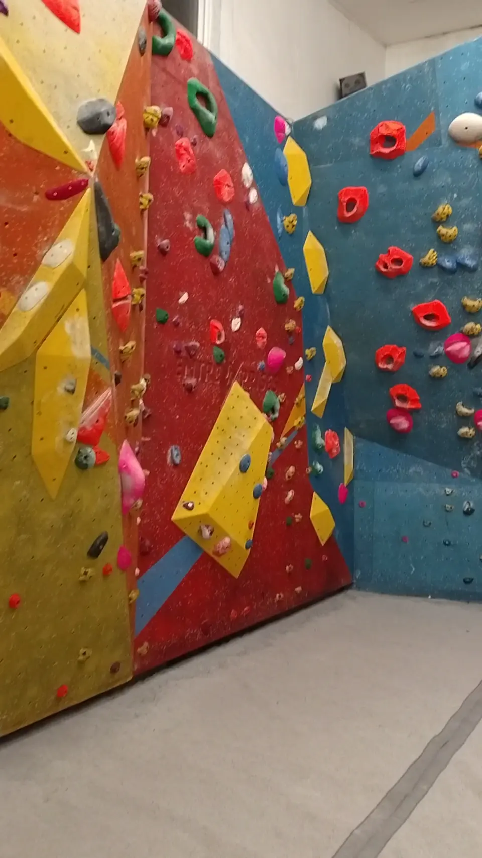 Red and blue corner of a bouldering room with yellow volumes