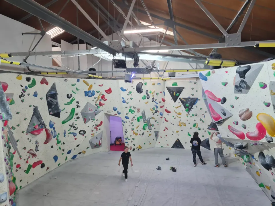 Bouldering hall with angled walls, volumes and grey matting