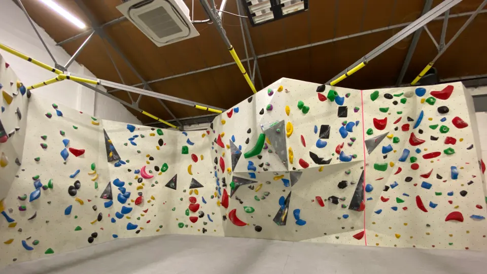 Bouldering walls with grey volumes under a timber roof
