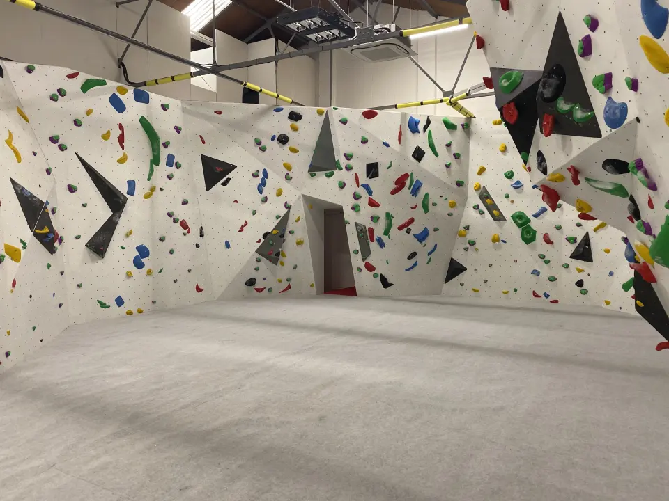 Corner of the bouldering area with black volumes and padded floor