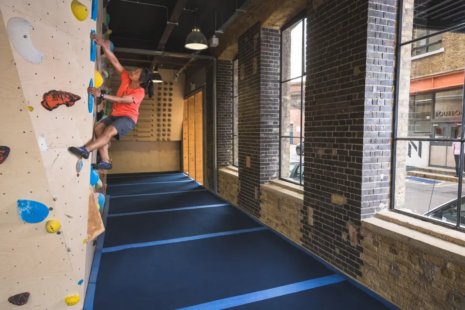 Plywood bouldering wall running along the tall street windows