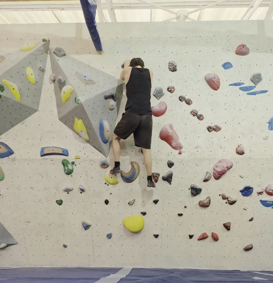 Climber on a grey wall with triangular volumes
