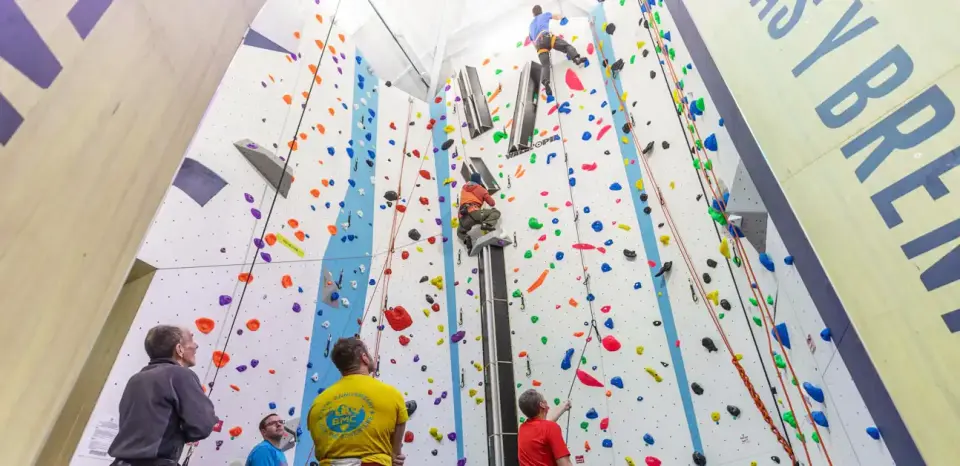 Climbers and belayers below the tall lead walls