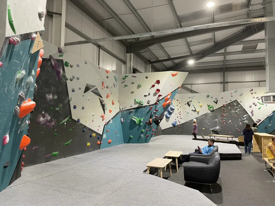 Grey and teal bouldering walls with sofas on the matted floor