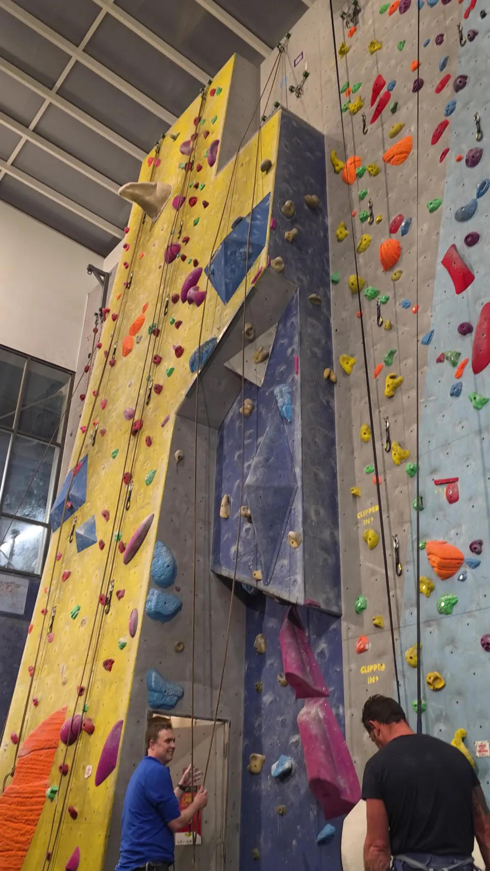 Yellow and blue roped walls with belayers below