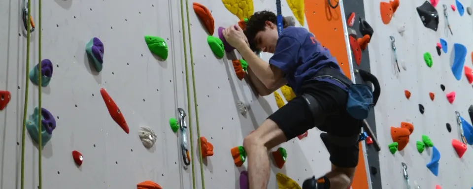 Climber on a white roped wall with an auto-belay line