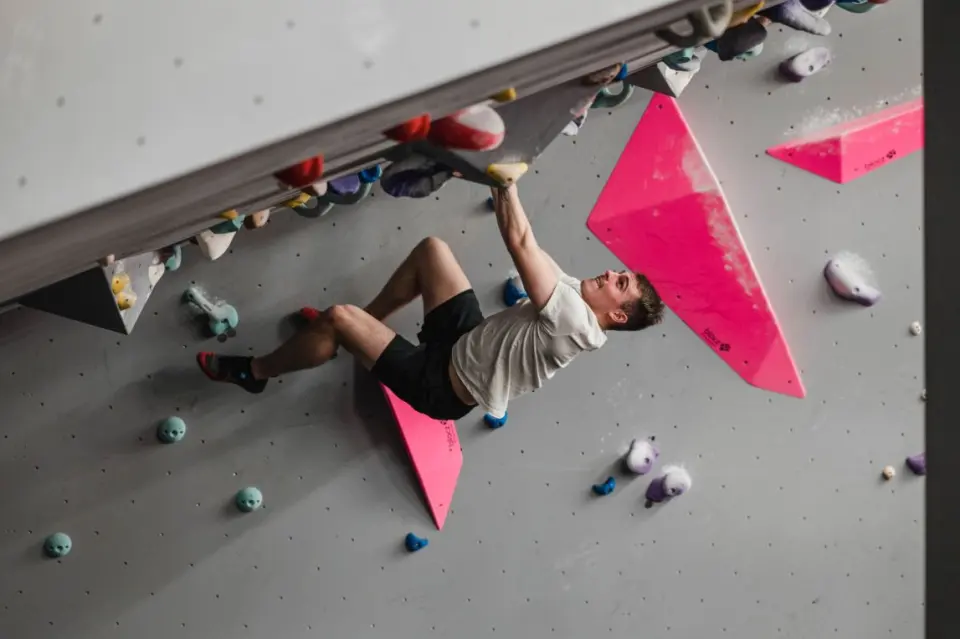 Climber under a steep overhang with pink volumes
