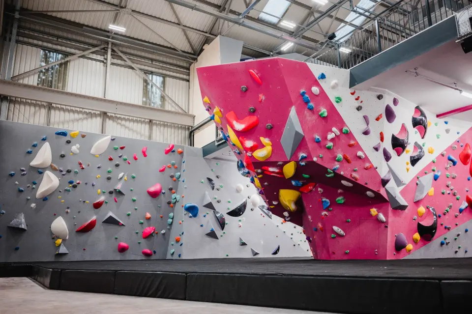 Pink and grey bouldering prow under the high hangar roof
