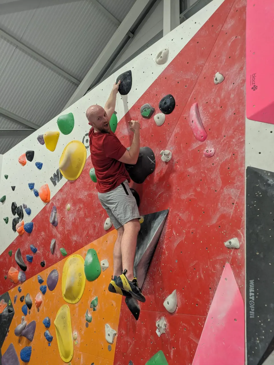 Climber on a red bouldering wall with yellow holds