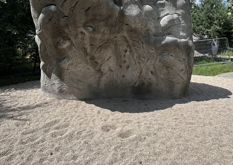 Featured face of a concrete boulder above sand