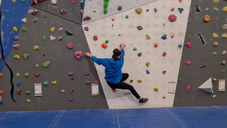 Climber on the grey and white wall with blue edges