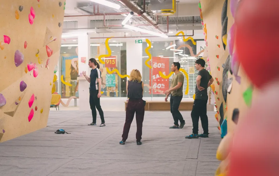 Bouldering walls either side of the hall, with the shopping centre beyond the windows