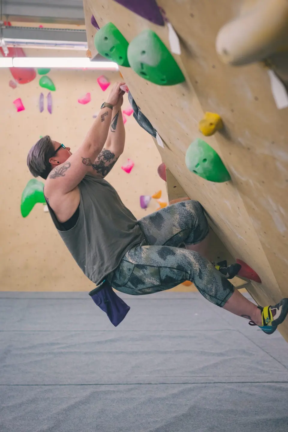 Climber on an overhanging boulder with green volumes